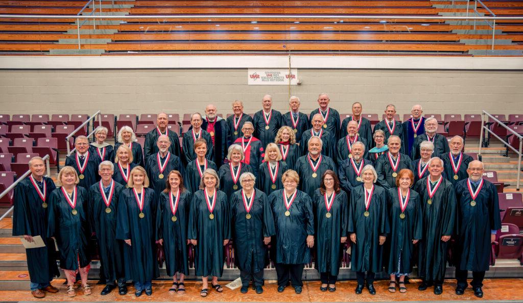 Group of SNU Golden grads standing in graduation regalia inside SNU's Sawyer Center